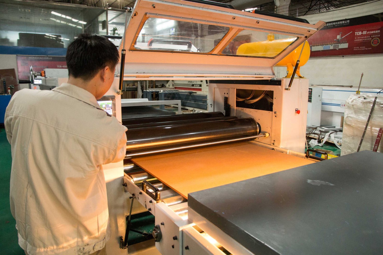 Founder working with edge banding machinery on factory floor