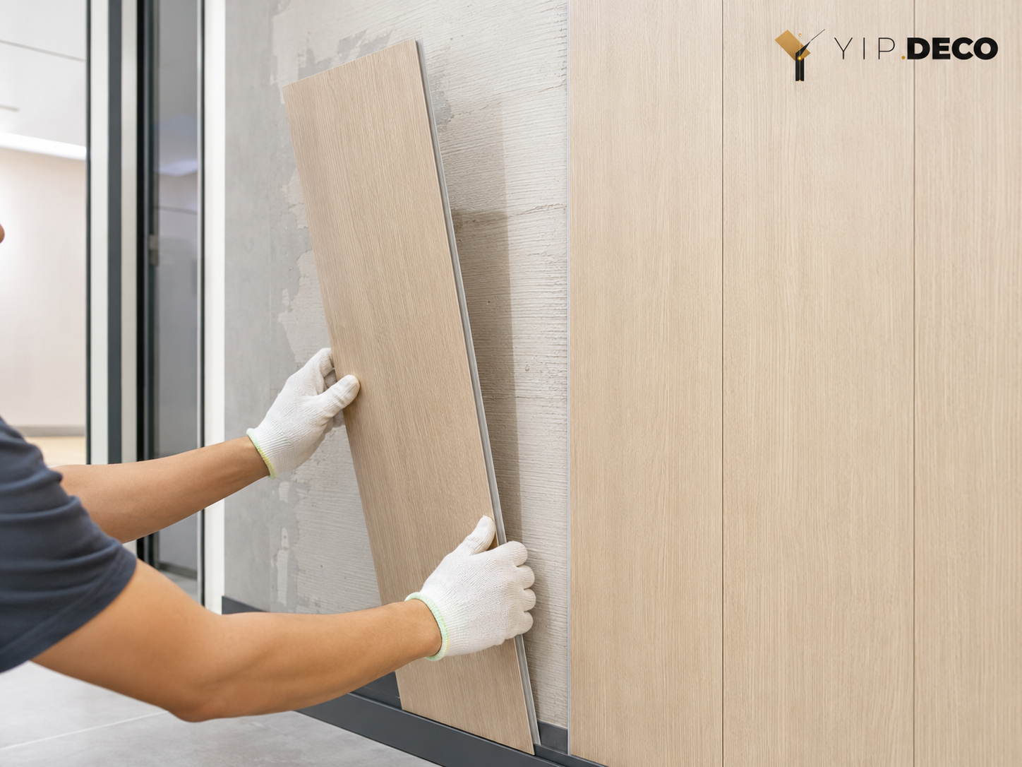 Worker click-fitting an SPC wall panel over an existing wall during a renovation